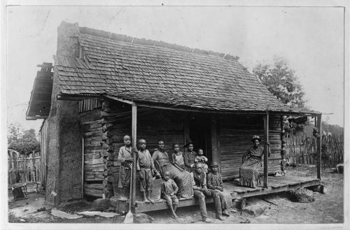 Slave cabin with large group of slaves. Houses such as these provided very little protection during winters. 